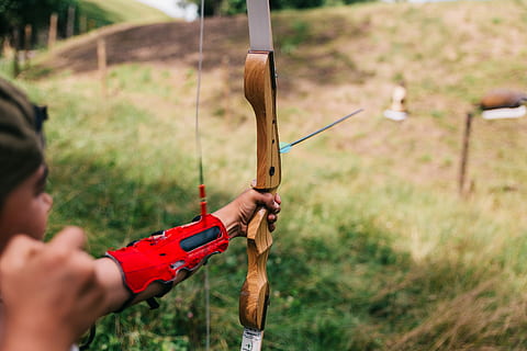 person using bow aiming person from afar during daytime, man holding compound bow HD wallpaper