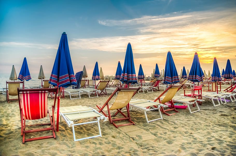 assorted-color chair with umbrella on beach near the water during golden hour HD wallpaper