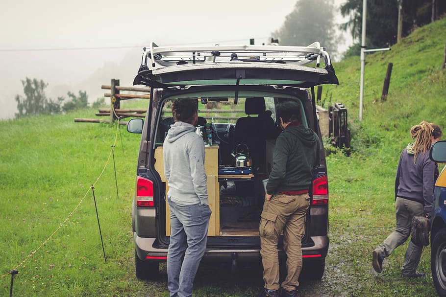 people standing at the back on an open vehicle, two men standing at the back of black van HD wallpaper