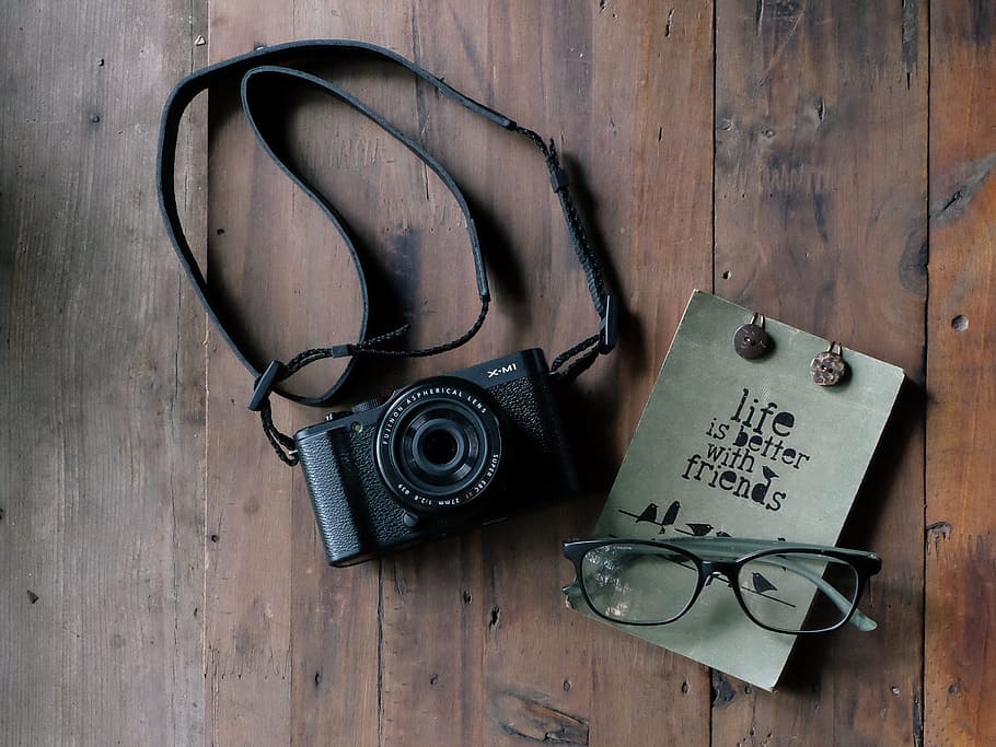 black SLR camera near black reading glasses on brown wooden surface HD wallpaper