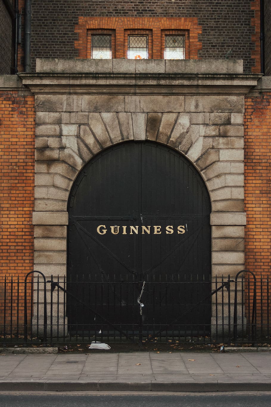 black steel fence, closed black wooden Guiness door, brick, wall HD wallpaper