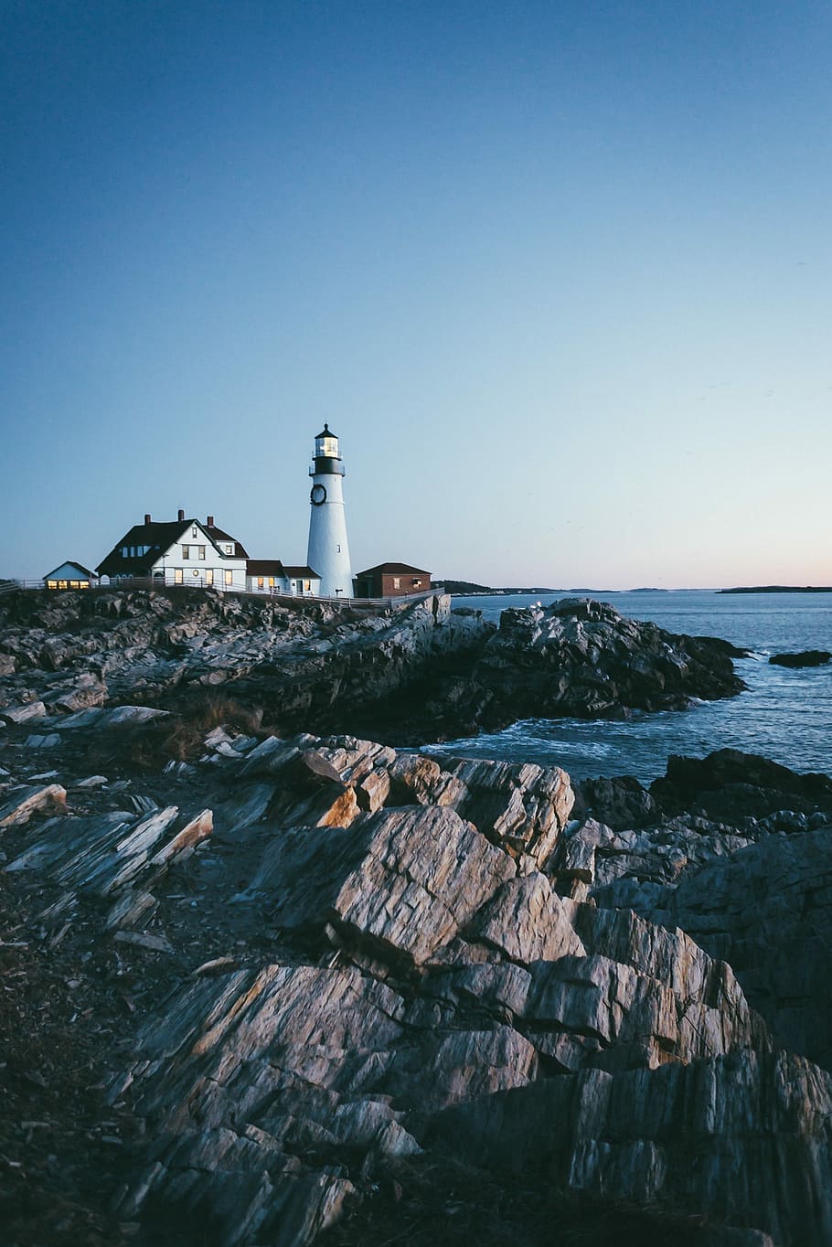 lighthouse beside body of water under blue sky, lighthouse beside ocean under clear blue sky during daytime HD wallpaper
