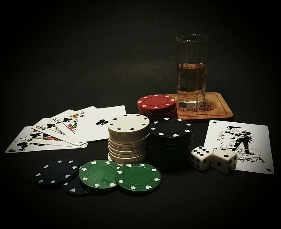 playing cards, poker chips, and half filled glass on table, card game