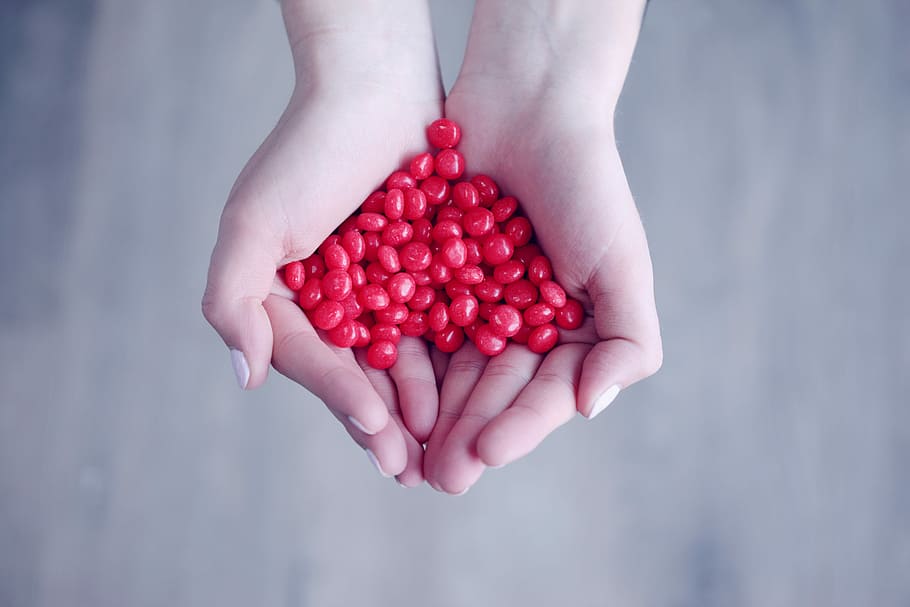 person holding red candies on her palms, person holding red cherries HD wallpaper