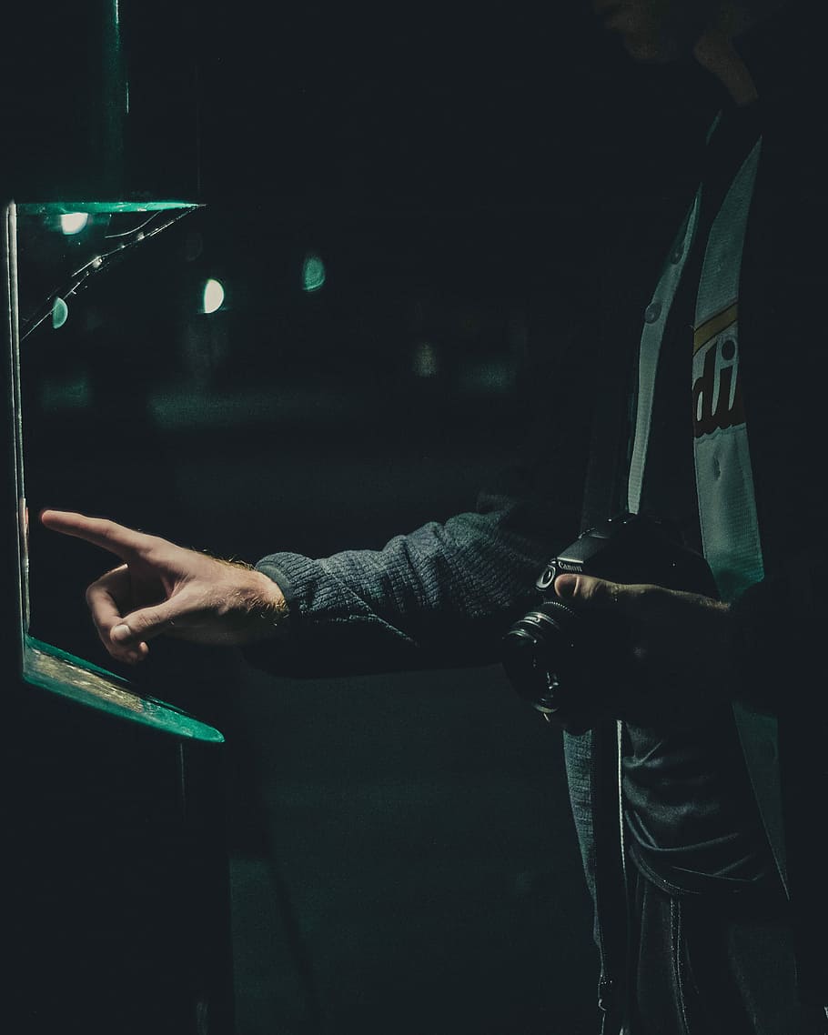 silhouette photography of man holding camera while attempting to operate machine, person holding black DSLR camera using green lighted machine HD wallpaper