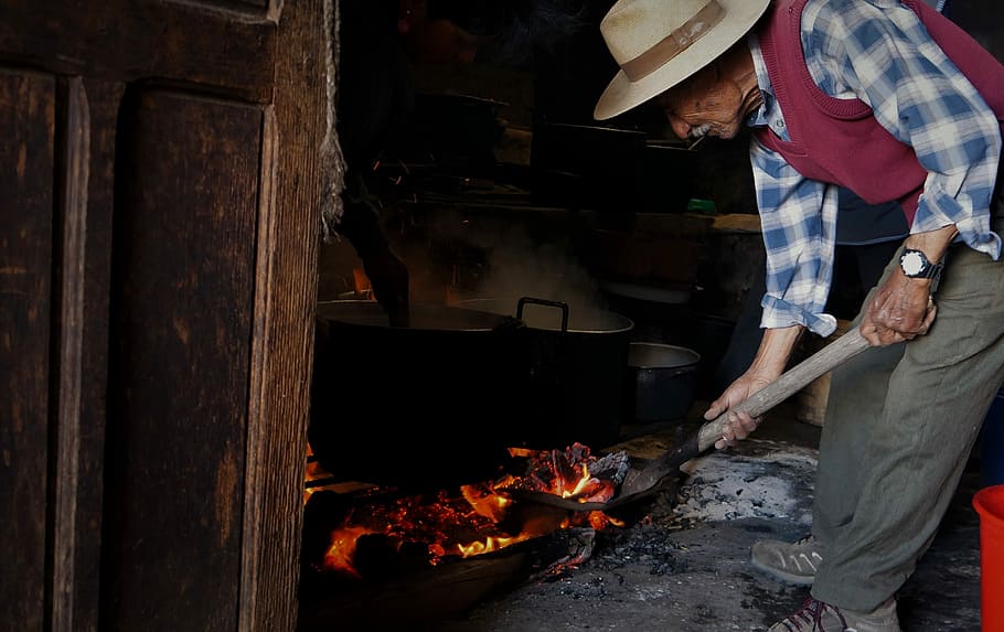 man cooking on pot, man holding shovel standing near cooking pot HD wallpaper