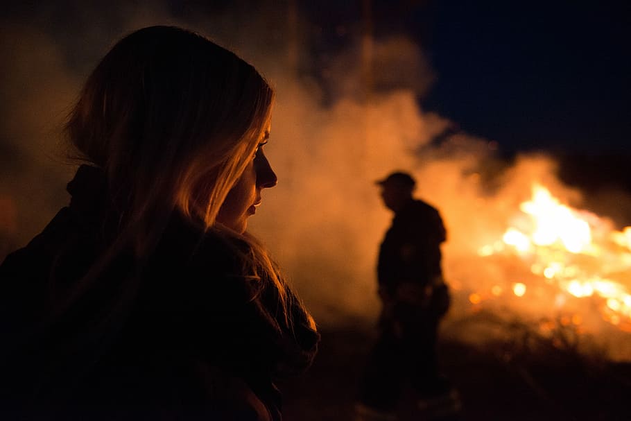 silhouette photography of man and woman nearby bush fire, shallow focus photography of woman looking at fire HD wallpaper