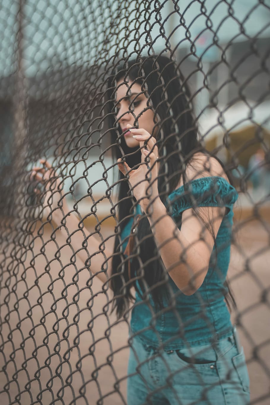 photography of woman touching gray metal fence, shallow focus photography of woman in green off-shoulder top holding black steel cyclone fence HD wallpaper