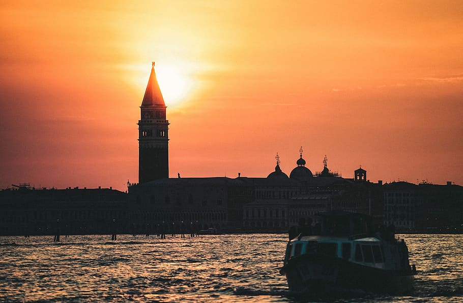 ship cruising body of water during daytime, silhouette photo of boat near concrete chapel during golden hour HD wallpaper