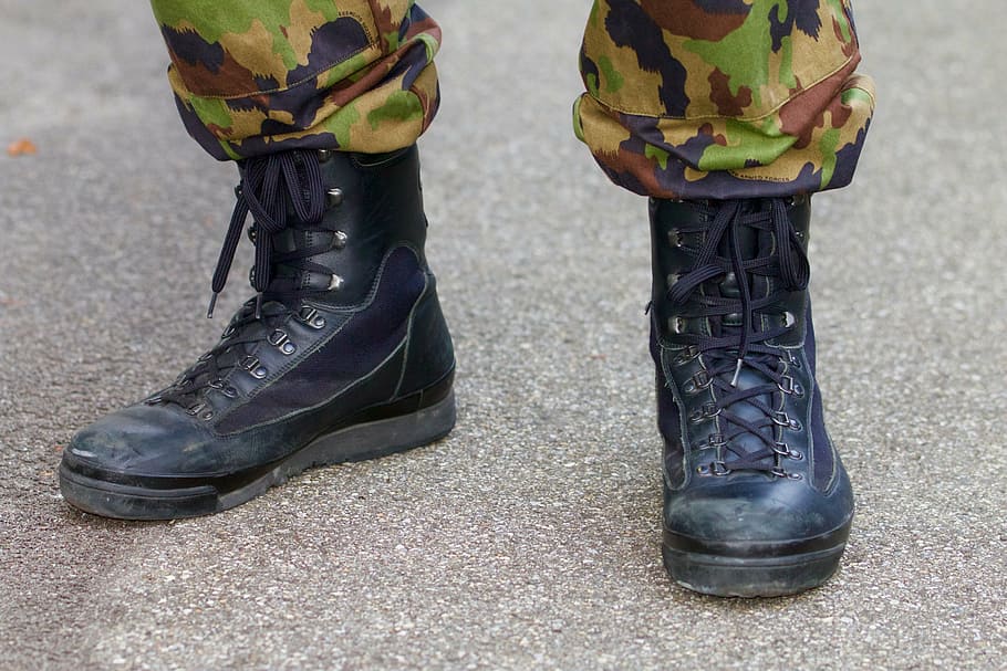 person wearing black leather combat boots standing on the ground