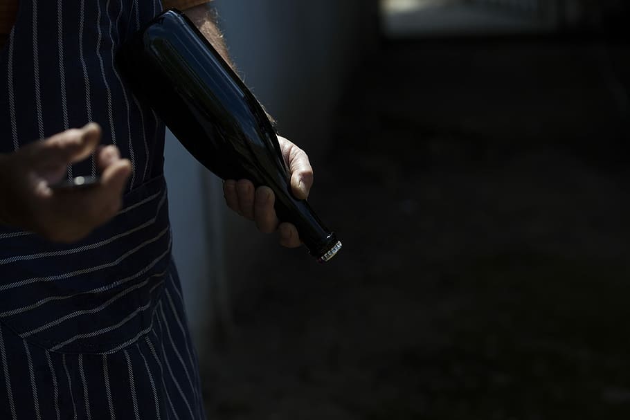 person holding black glass bottle, person holding amber glass beverage bottle HD wallpaper