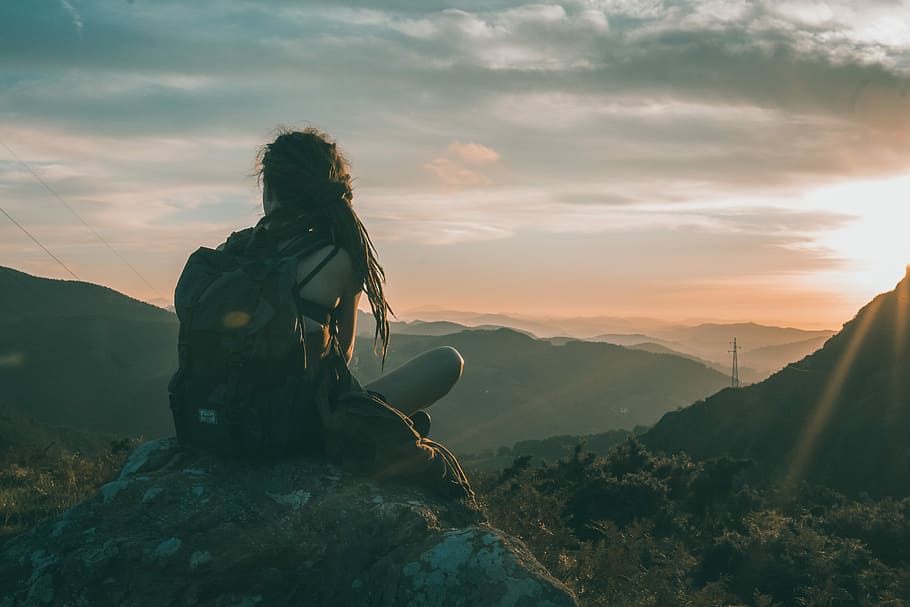woman sitting on rock carrying black backpack, woman sitting on rock during sunrise HD wallpaper
