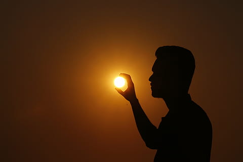 forced perspective photo of silhouette of man holding sun, sunset HD wallpaper