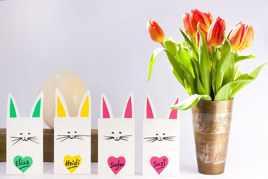 orange and yellow Tulip flowers on vase beside four cats paper bags