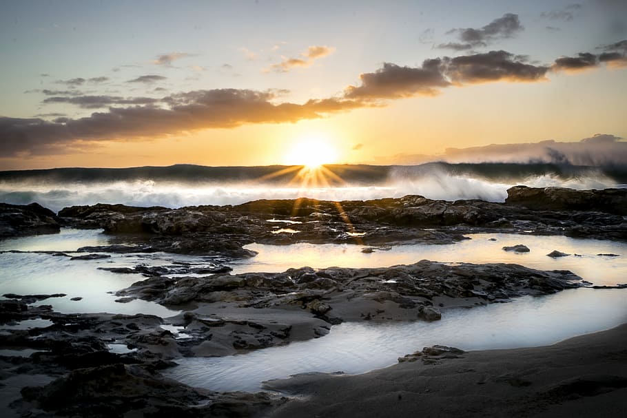 wave of water on rocks, silhouette photo of rock formation during golden hour HD wallpaper