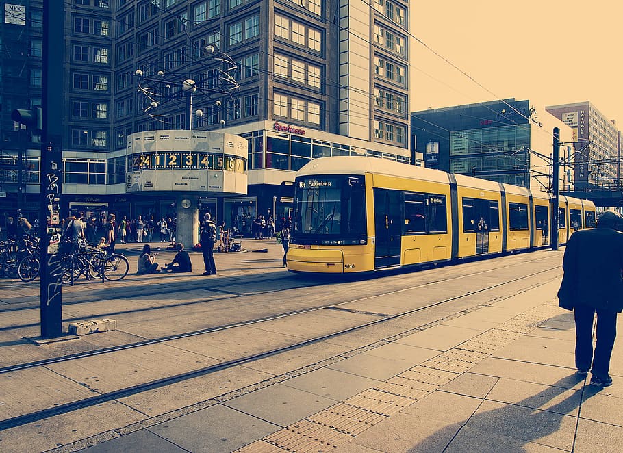 Selective Color Photography of Yellow Train Near Concrete Buildings HD wallpaper