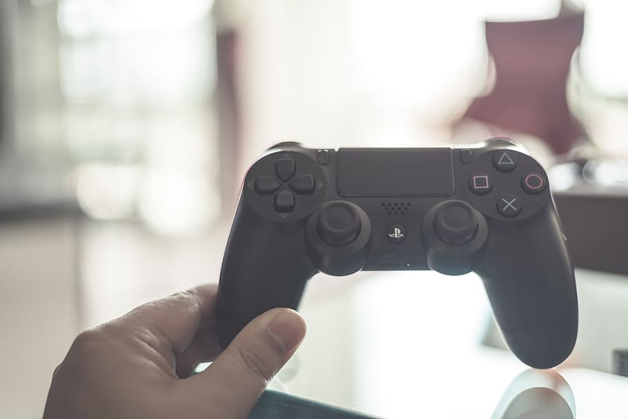 person holding black PlayStation DualShock 4, controller, hand