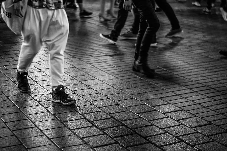 men walking on concrete tiled ground, people walking on brick flooring in grayscale photography