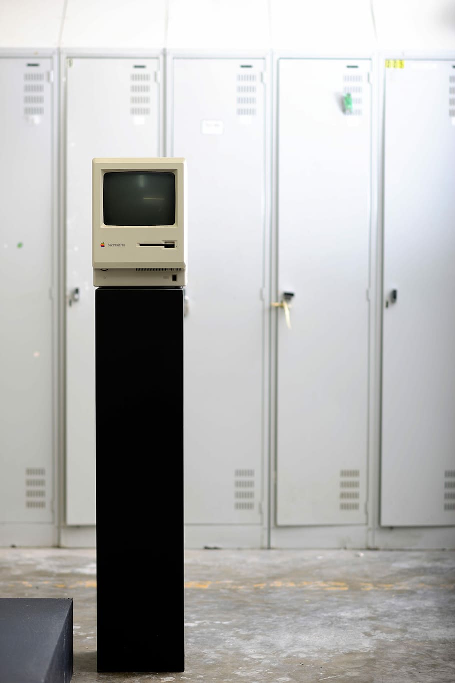 gray CRT monitor beside white locker, white CRT monitor on black stand near white locker