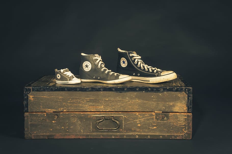 three unpaired Converse All-Star shoes on wooden trunk, sneakers