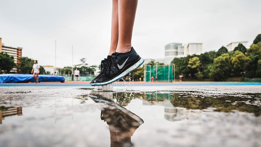 person wearing black-and-white Nike low-top sneakers, person jumping over water during daytime HD wallpaper