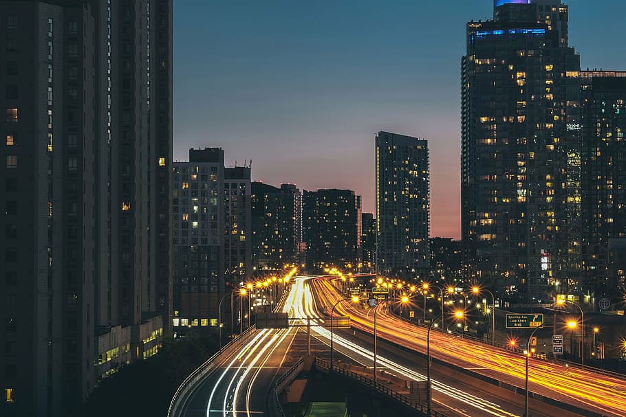 time-lapse photography of road between high rise buildings during blue hour