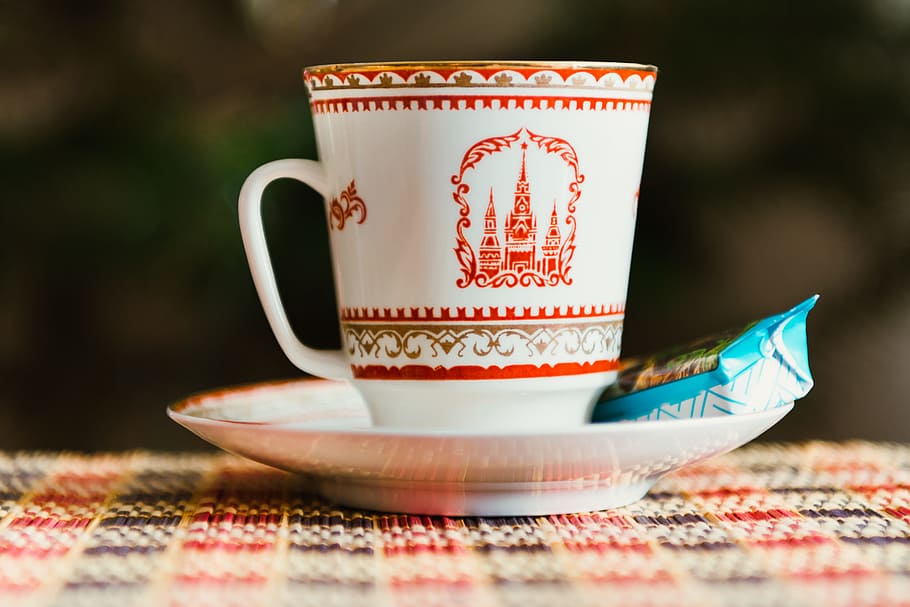 selective focus photography of white-and-red teacup on saucer with blue labeled food pack, white and red ceramic mug on saucer HD wallpaper