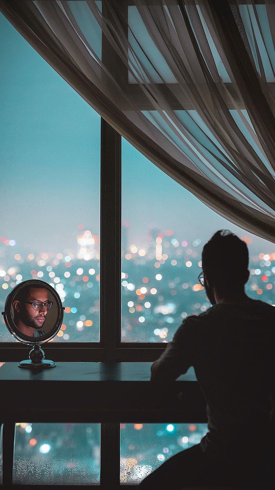man sitting in front of black wooden table with face reflecting on round vanity table mirror, man sitting infront of black table in doors HD wallpaper