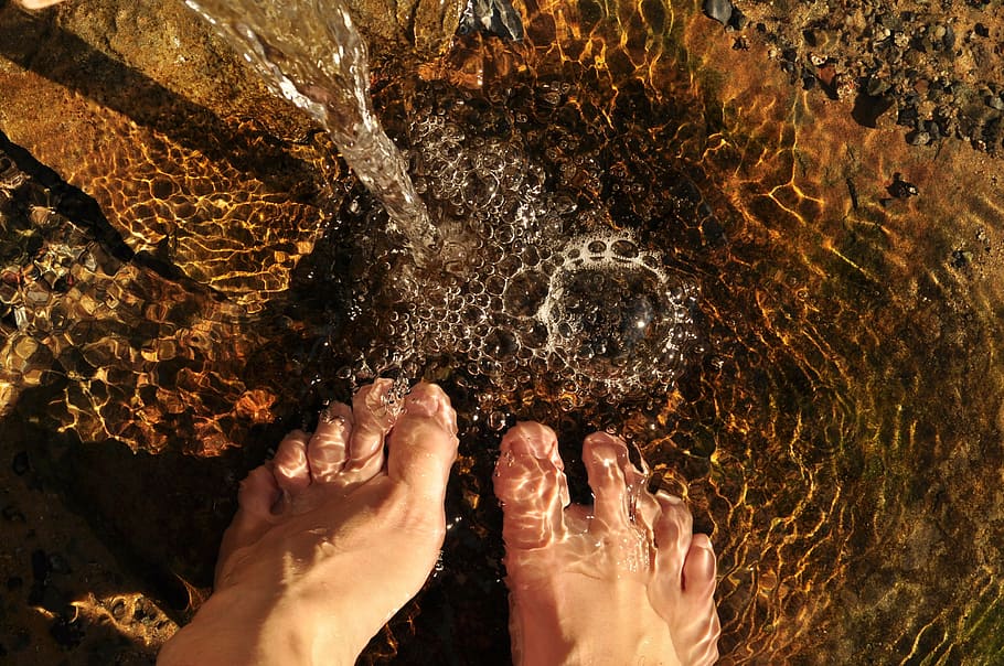 closeup photo of human feet on body of water, feet in the water