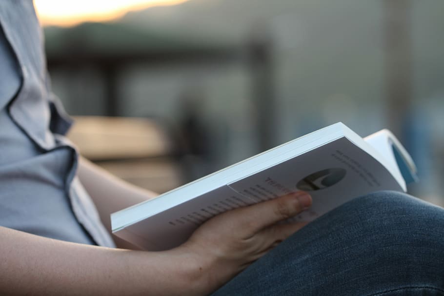 person reading while holding book on lamp, closeup, photo, reading man HD wallpaper