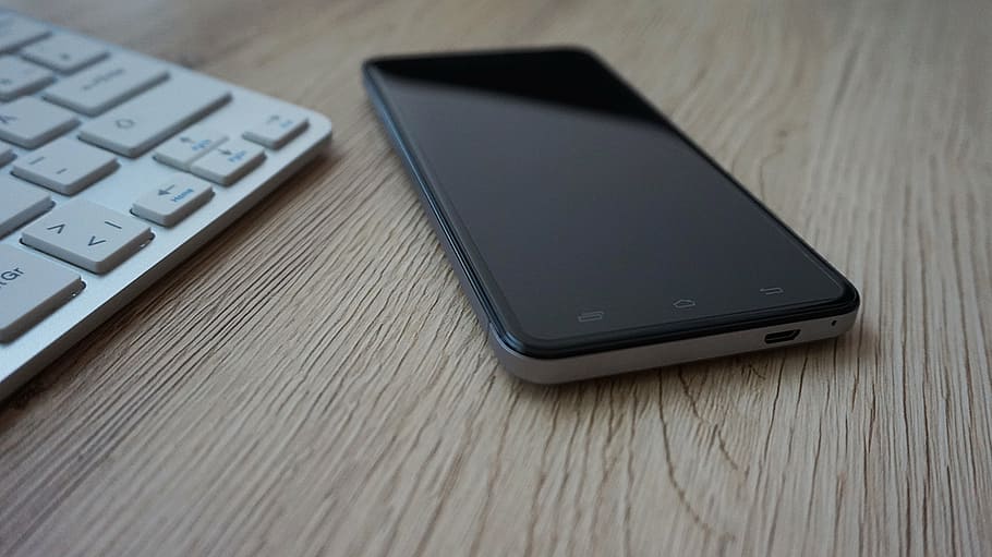 black Android smartphone on brown wooden board, keyboard, desk HD wallpaper