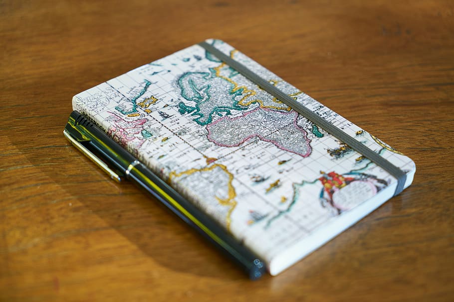 white map covered book and pen on brown wooden surface, notebook HD wallpaper