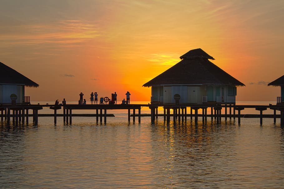 people standing on dock between houses at golden hour, sunset HD wallpaper