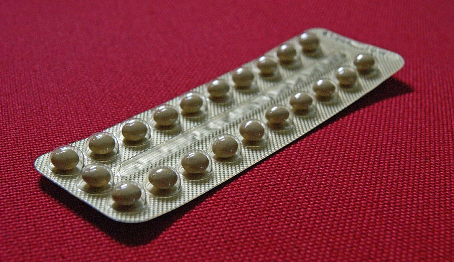 brown medication blister pad on red pad, contraceptive pills