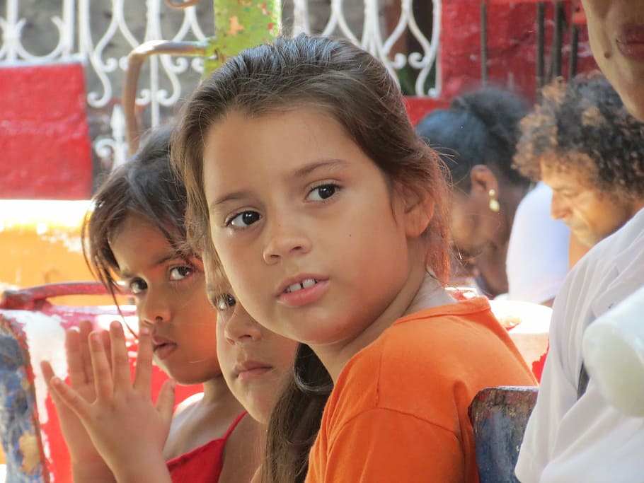 girl in orange top surrounded by people, children, cuba, latin