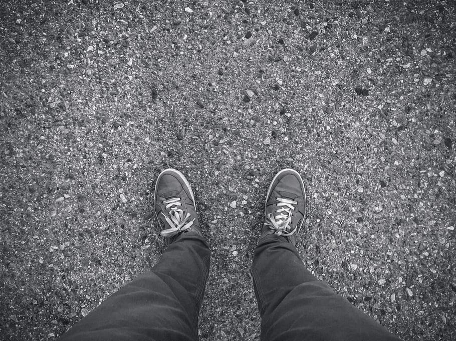person in black-and-white lace-up shoes, feet, concrete, sneakers