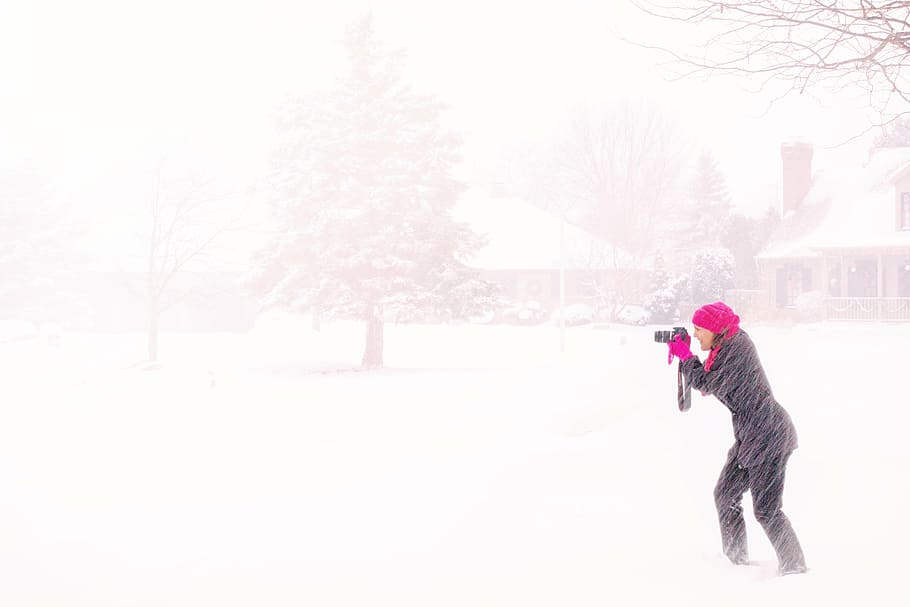 woman wearing black coat white holding camera in the middle of snow storm, HD wallpaper