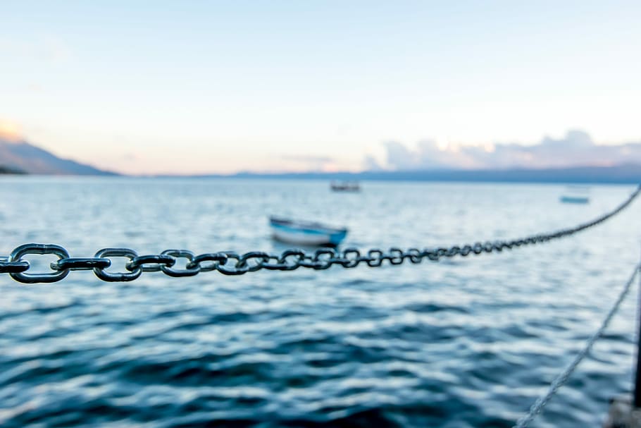 boat on sea water under sunny sky, selective focus photography of chain rope near body of water HD wallpaper