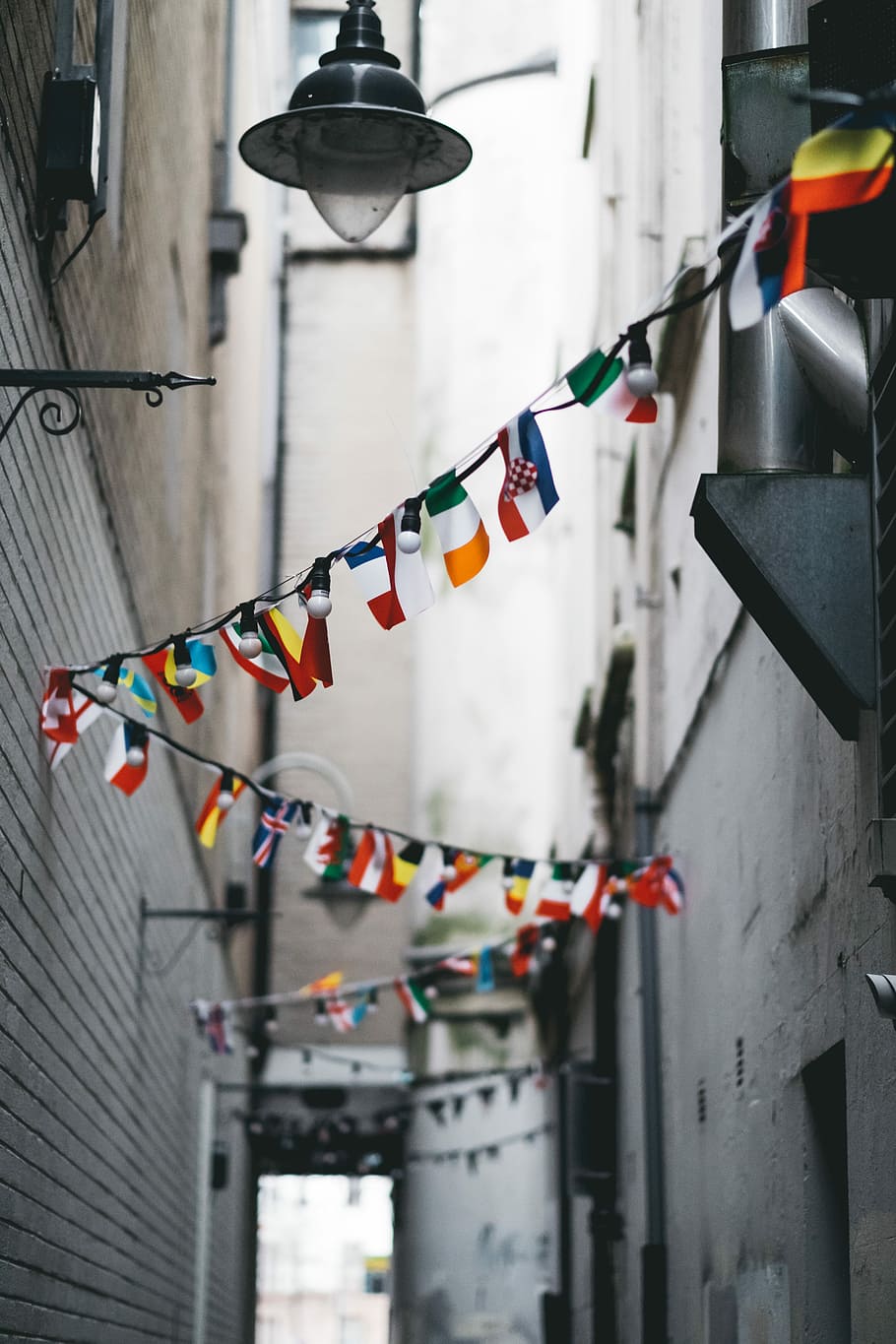 multicolored buntings on pathway, assorted flag pennants, street light