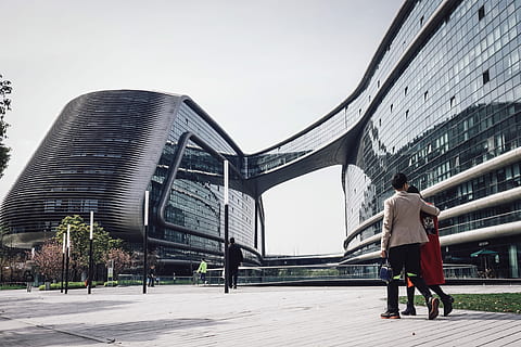 architectural photography of glass windows of conjoined building, man in gray suit jacket beside woman walking on the floor during day time HD wallpaper