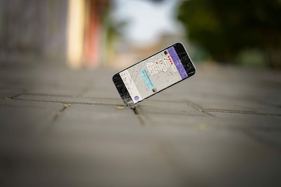 selective focus photo of iPhone balance on brick pavement, cracked black smartphone on asphalt stone HD wallpaper