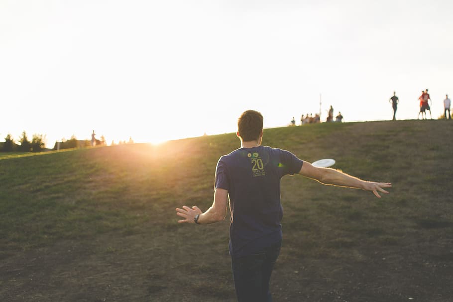 man walking on green grass field, photo of man playing flying disc HD wallpaper
