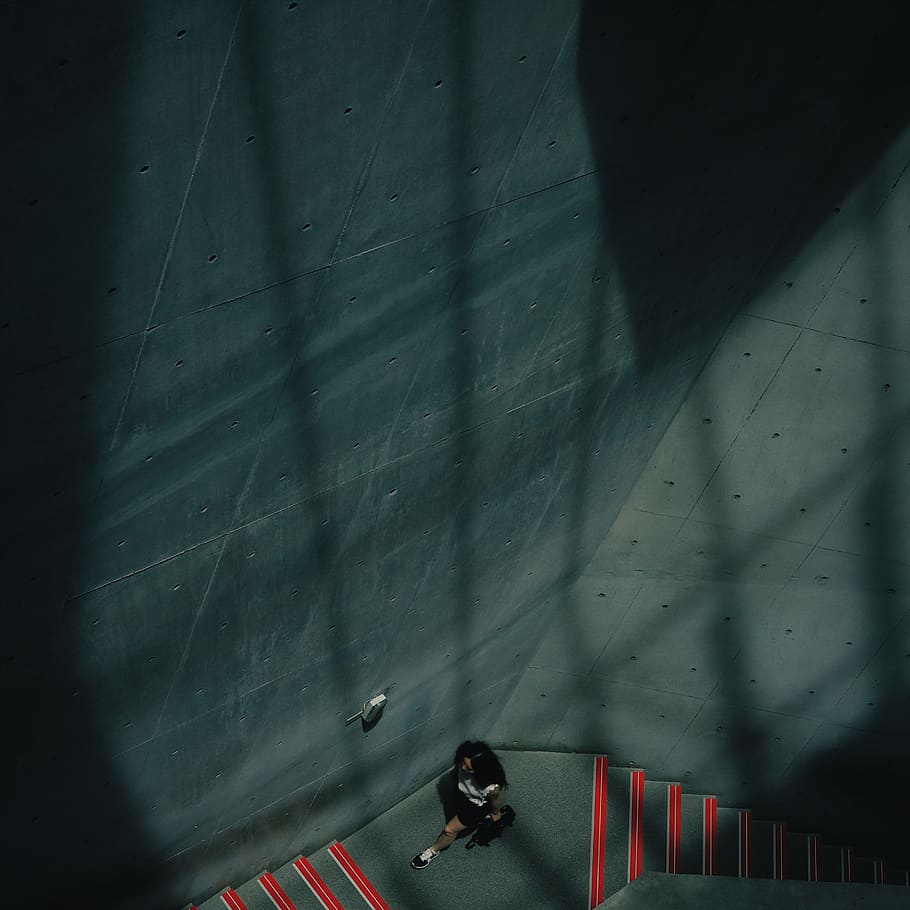 aerial photography of couple kissing in stair, aerial photography of woman sitting on grey floor beside grey wall inside the building HD wallpaper