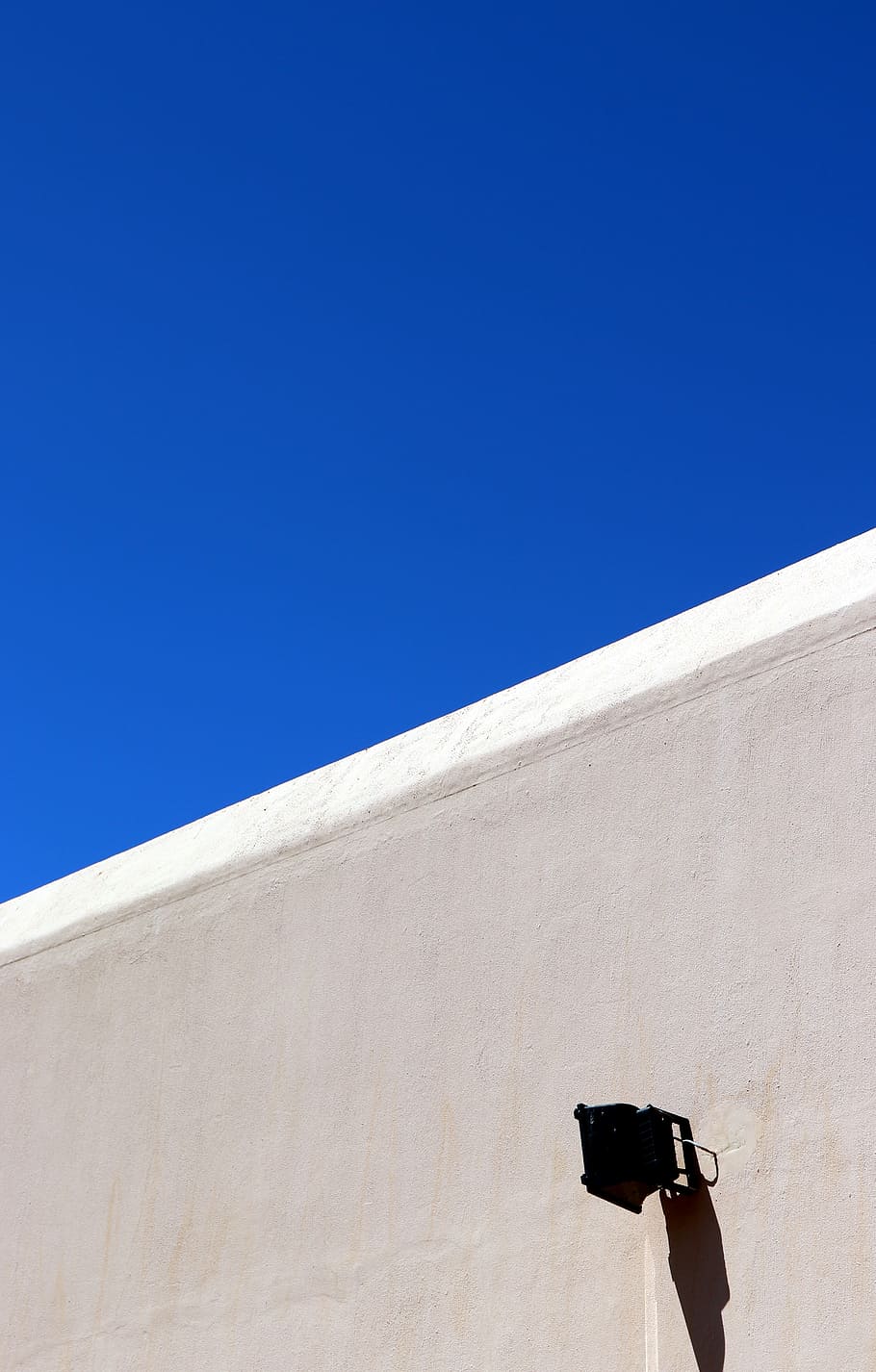 gray concrete wall under blue sky, black work light on wall, white HD wallpaper