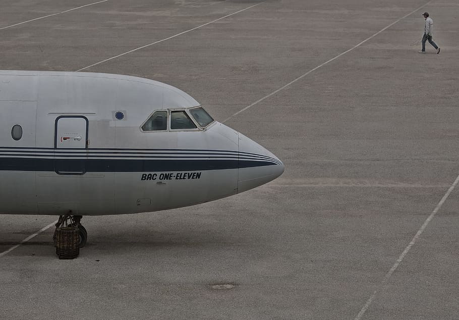 plane on airport, man walks beside white airplane during daytime HD wallpaper