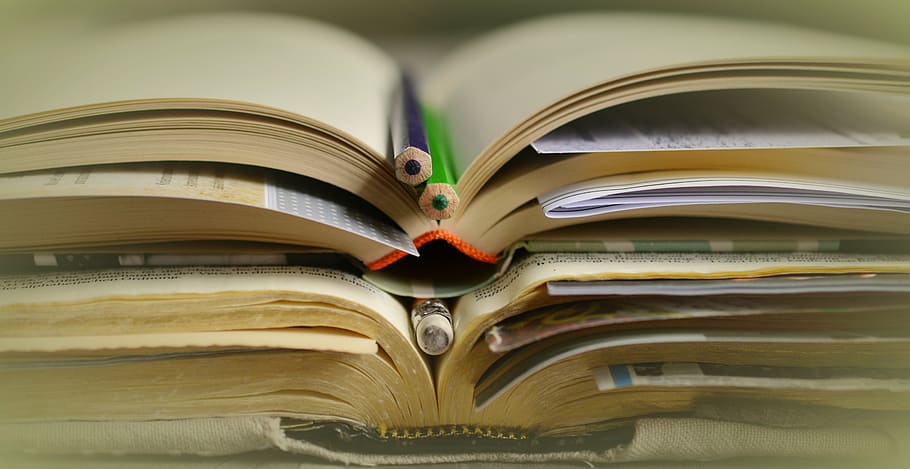 closeup photography of two purple and green color pencils on brown book HD wallpaper