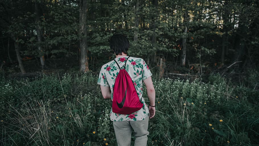 man walking along the forest, person showing Nike drawstring bag