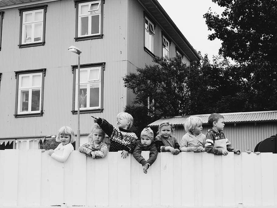 grayscale photo of seven children standing in wooden fence near house, group of kids on wooden fence HD wallpaper