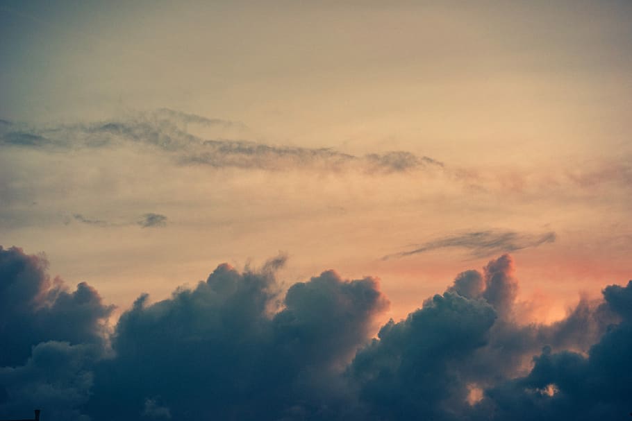 photo of dark clouds in a peach colored sky, sea of clouds during twilight