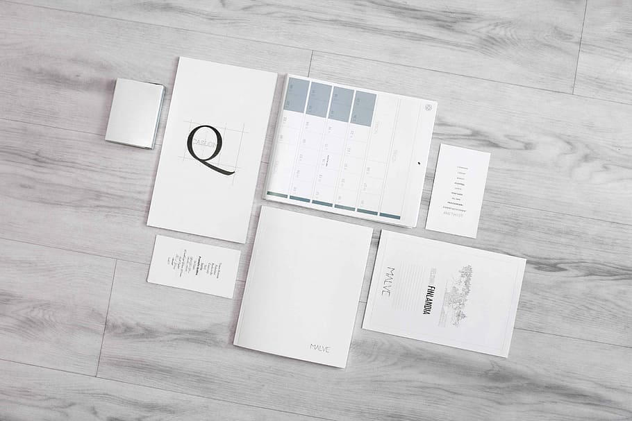 flat-lay photography of white printer papers, grayscale photo of calendars on hardwood floor tile